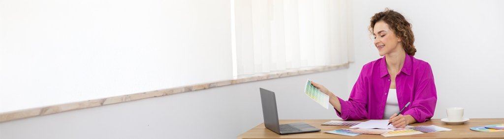Eine junge Frau arbeitet mit Farben am Laptop. | A young woman works with colors on a laptop. | Une jeune femme travaille avec des couleurs sur un ordinateur portable.